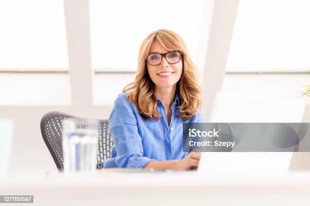 Attractive Mature Using Laptop While Sitting At Desk At Home Stock Photo - Download Image Now