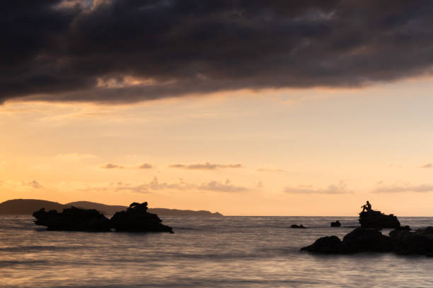 istock Rock silhouettes in the sea at sunset 1271151890