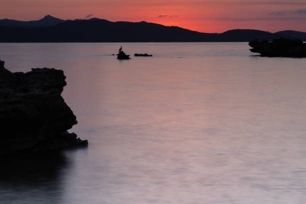 istock Rock silhouettes in the sea at sunset 1271151924