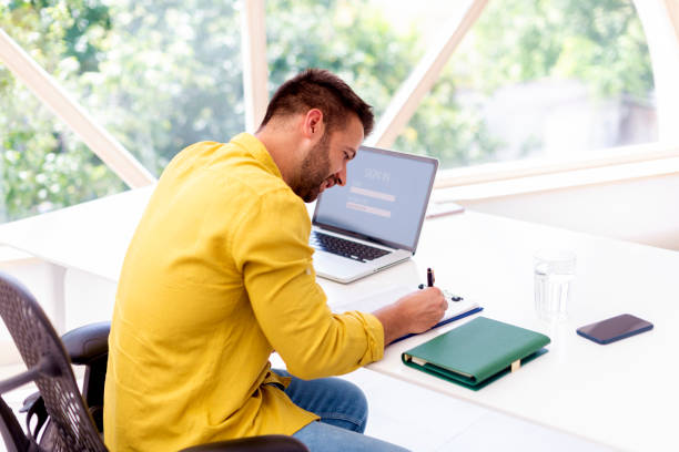 istock Businessman writing something while sitting at office desk at home 1271154428