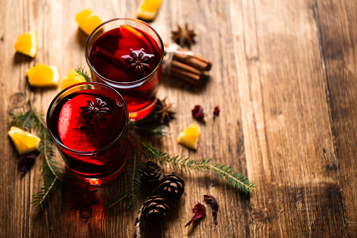 Wine-filled glasses surrounded by pine needles, spices and orange slices