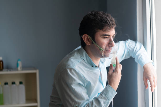 Mature Adult Man Using Nebulizer And Looking Through Window stock photo