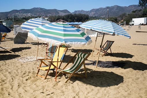Beach umbrellas and sun loungers on an empty beach in Malibu after a busy weekend and holiday.