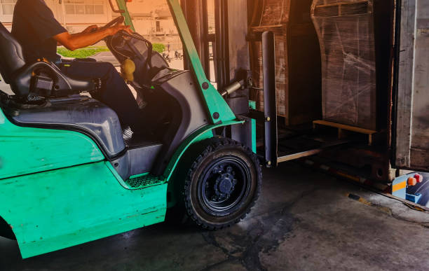 istock Worker driving forklift loading shipment carton boxes goods on wooden pallet at loading dock from container truck to warehouse cargo storage in freight logistics, transportation industrial, delivery 1271161809