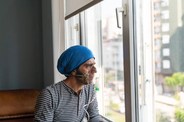 Mature Adult Man Using Nebulizer And Looking Through Window Mature adult man using nebulizer and looking outside through window. He is wearing casual clothing. Shot indoor  with a full frame mirrorless camera. COPD stock pictures, royalty-free photos & images