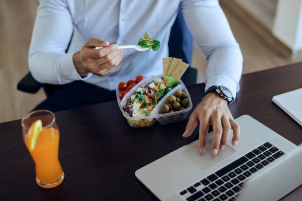 istock Unrecognizable businessman using computer while having healthy meal in the office. 1271164075
