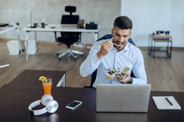 istock Young businessman eating healthy food while using computer on lunch break in the office. 1271164155