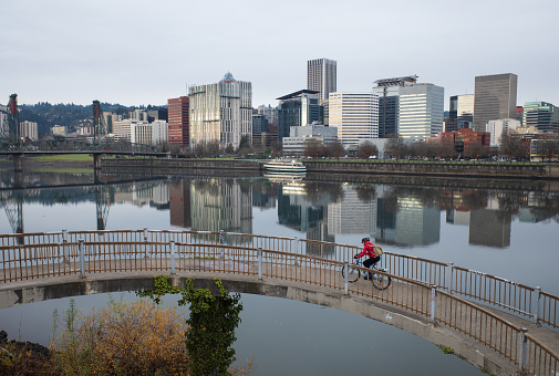 A biker riding up the Morrison Bridge Pedestrian and Bike Ramp with Downtown Portland in the background