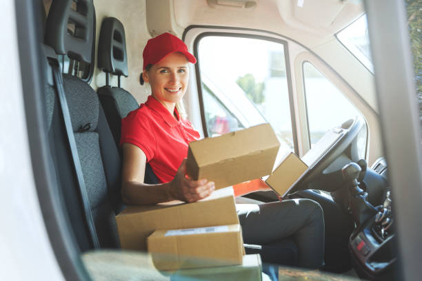 istock female delivery service worker in red uniform sitting in van with boxes. smiling at camera 1271168403