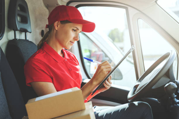 istock delivery woman in red uniform sitting in van and writing documents 1271168447