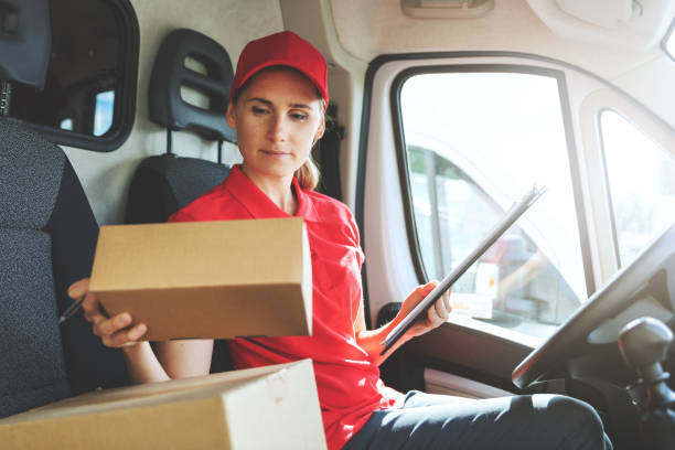 istock female delivery service worker in red uniform sitting in van and working with packages 1271168502