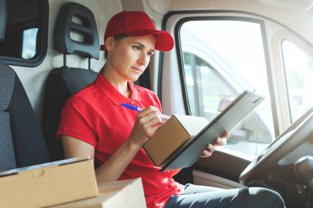istock delivery woman in red uniform sitting in van and writing documents 1271168607