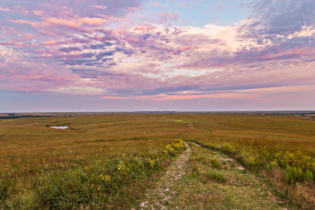 Setting sunlight bathes the sky in soft pastels over Tallgrass Prairie National Preserve near Strong City, Kansas.