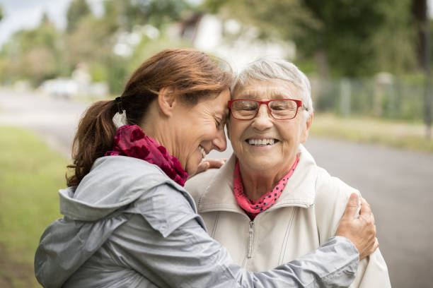 femme aîné et soignant heureux marchant à l’extérieur - parent denfant adulte photos et images de collection