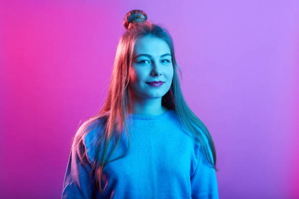 istock Attractive lady standing isolated over pink neon background and looking directly at camera, expressing positive emotions, wearing casual sweater. 1271176206