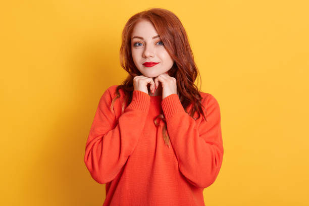 istock Charming attractive red-haired young female with cute expression, looking at camera, smiling cheerfully, feeling relaxed and happy, wearing casual orange sweater. 1271176387
