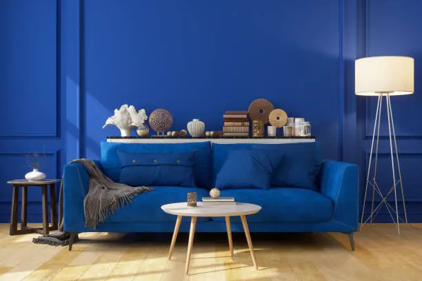 Blue Sofa In Front Of The Blue Wall With Decorative Objects And An Electric Lamp