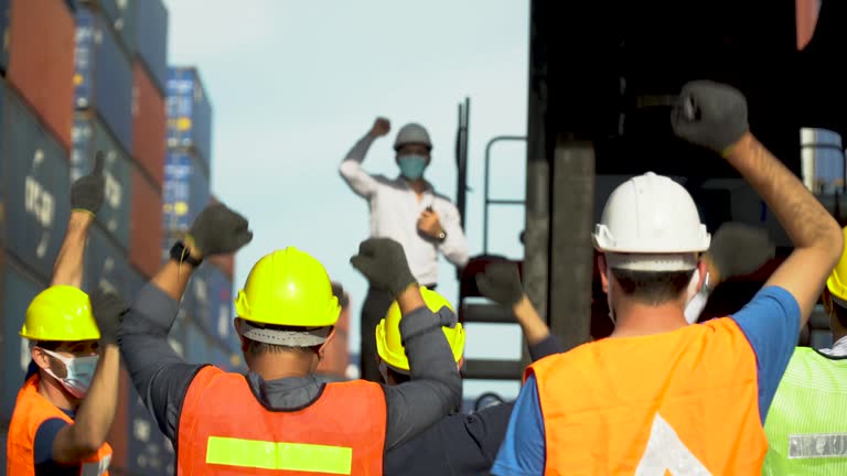 Workers protest in Cargo freight ship for import export logistic During corona virus or covid 19 outbreak . Group of protestors fists raised up in the air . Strike of labor in industry