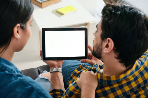 jeune couple retenant la tablette avec l’écran blanc pour l’espace de copie - laptop sofa men computer photos et images de collection