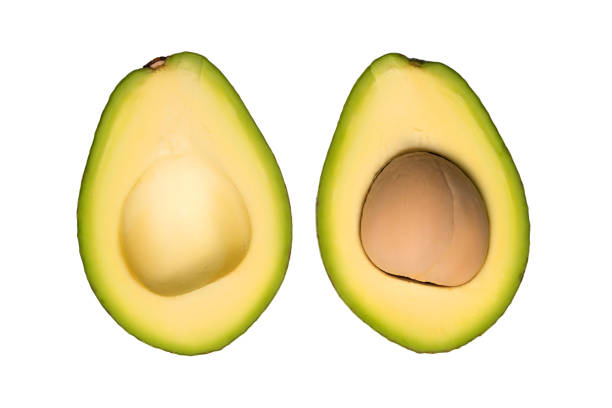 Perfectly Ripe Avocado Halved With Kitchen Knife on Wooden Cutting Board