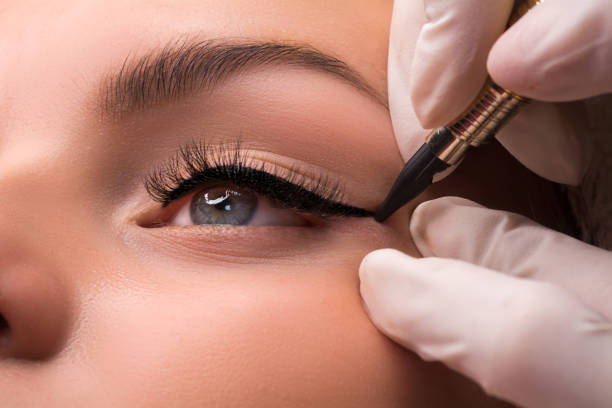 Permanent eye makeup close up shot. Cosmetologist applying tattooing of eyes. Makeup eyeliner procedure stock photo