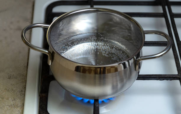 the water in a stainless steel pot is heated - blue flame natural gas fireplace imagens e fotografias de stock