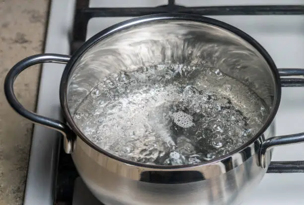 Boiling water in a stainless saucepan on a gas stove.
