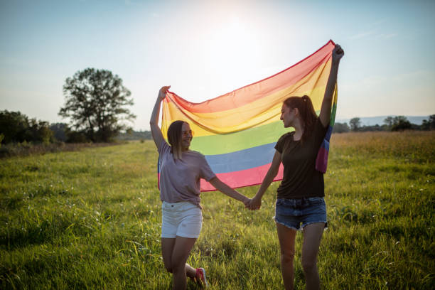 istock Lesbian couple with LGBT flag on a meadow 1271182401