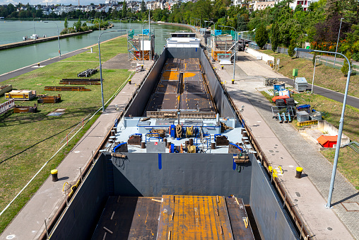 Double barge filled with sheets of thick metal, flowing into the river lock.