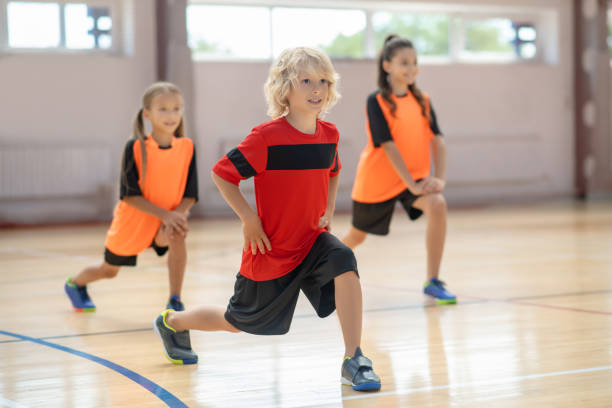istock Kids exercising in the gym and doing lungings forward 1271183695