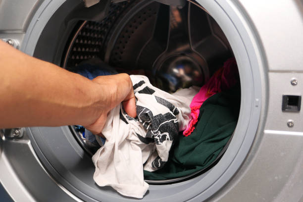 istock man putting shirt into washing machine. 1271183907