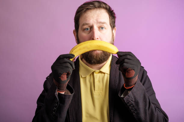 istock a bearded man holds a banana upside down to his face, making a sad grimace 1271187310