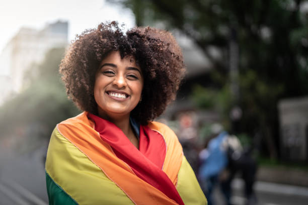 porträt einer glücklichen frau mit regenbogenflagge - homosexual gay man parade flag stock-fotos und bilder