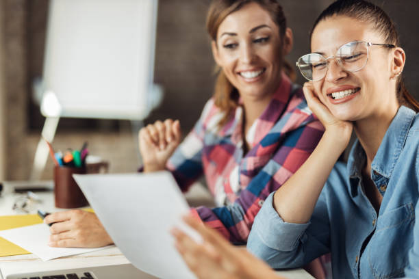 istock Young cheerful colleagues talking about reports while working at casual office 1271195059