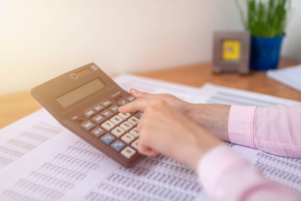 istock female accountant or banker making calculations sitting at office table with documents with tables on desk. Savings, finances and economy concept 1271198029