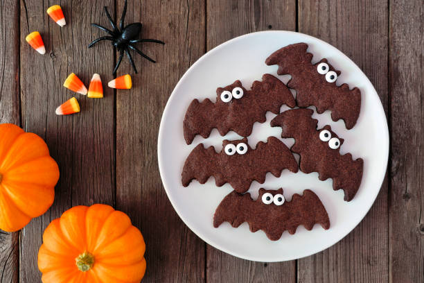 istock Chocolate Halloween bat cookies. Above view with decor on dark wood. 1271199052