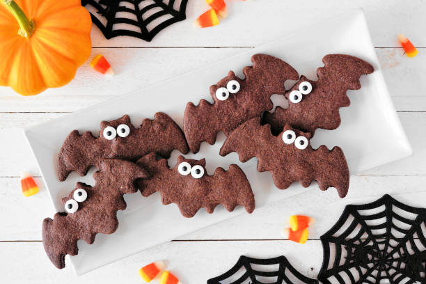 istock Chocolate Halloween bat cookies. Top view with decor over white wood. 1271199348
