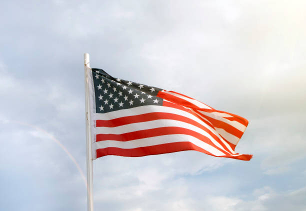 istock American flag on a blue sky with clouds background 1271201811