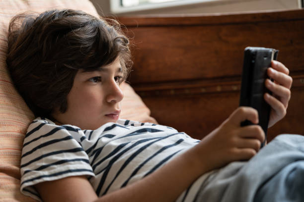 istock Close Up Portrait Of Elementary Schoolboy Sitting On Sofa And Using Smartphone 1271202640