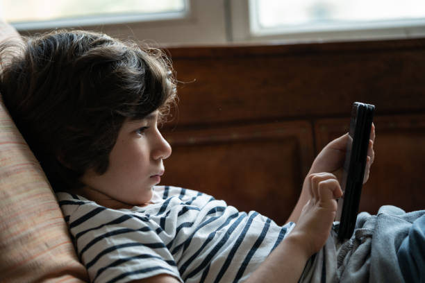 istock Close Up Portrait Of Elementary Schoolboy Sitting On Sofa And Using Smartphone 1271202641