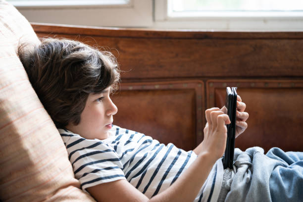 istock Close Up Portrait Of Elementary Schoolboy Sitting On Sofa And Using Smartphone 1271202735