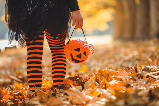 Little girl in witch costume having fun outdoors on Halloween trick or treat