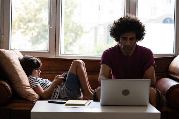 istock Father Working At Home While Son Using Smartphone In Living Room 1271202955