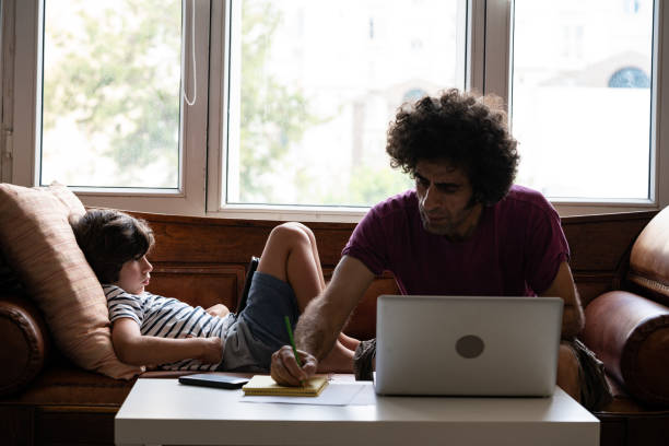 istock Father Working At Home While Son Using Smartphone In Living Room 1271203060