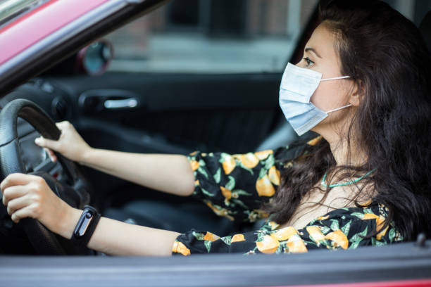 istock Woman with protective mask driving a car. Drive safe! 1271204817