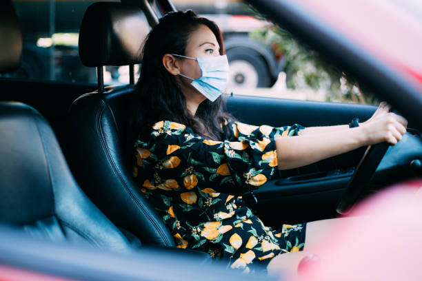 istock Woman with protective mask driving a car. Drive safe! 1271205413