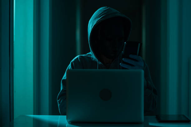 istock Man Wearing Hooded Shirt And Mask Using Laptop In Dark To Hack 1271207486