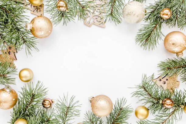 Photo of Christmas frame, pattern made in gold and and gold glass Christmas balls on white background. Holiday and celebration concept. Top view. Flat lay