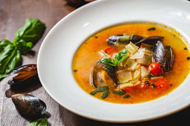 sopa con mejillones y verduras en plato blanco sobre mesa de madera. de cerca - caldo de pescado fotografías e imágenes de stock