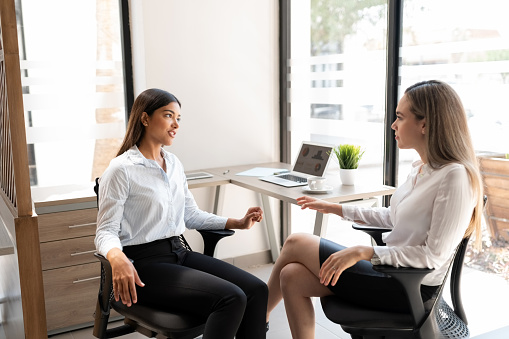 Two female business partners discussing over a new project at office desk
